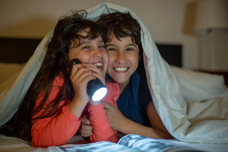 Kids using a flashlight under a blanket during a power outage
